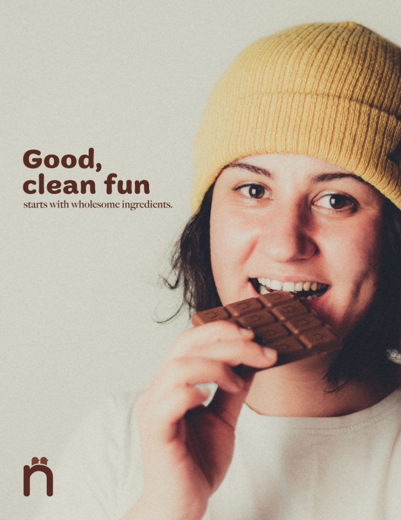 Image of a woman smiling biting into a chocolate bar. There is text that reads "Good, clean fun... starts with wholesome ingredients."